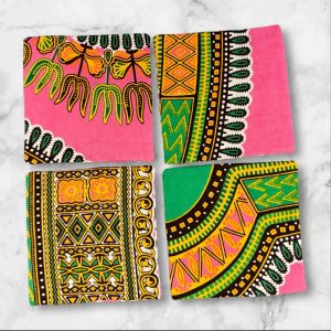 A set of four 4.5-inch square reversible fabric coasters with a pink and green African print on one side and a batik petal print on the other, displayed on a marble background.