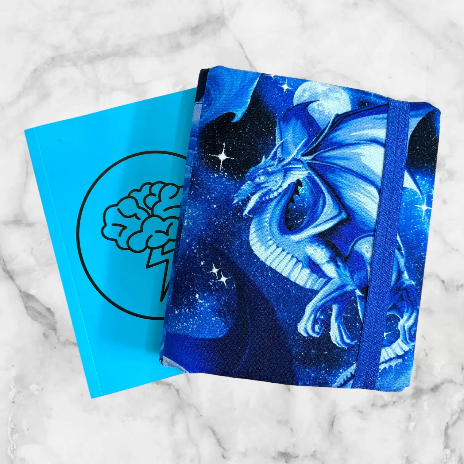 Mythical Blue Dragon notebook cover featuring a blue dragon against a cosmic night sky with a blue elastic band for closure.