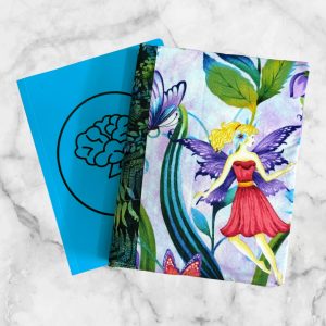 Enchanted Fairy notebook cover with a blonde fairy design, green elastic band, and vibrant floral and butterfly background.