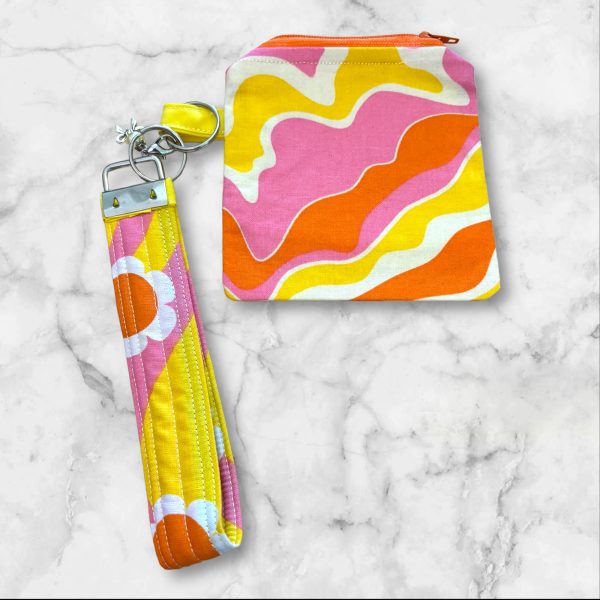 A Retro Waves Wristlet Key Fob and Card Wallet with swirling pink, orange, and yellow wave patterns.