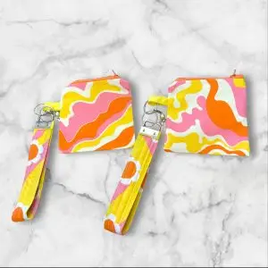 A Retro Waves Wristlet Key Fob and Card Wallet with swirling pink, orange, and yellow wave patterns.