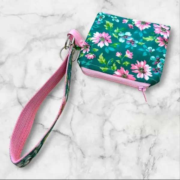 A Floral Fantasy Wristlet Key Fob and Card Wallet with pink and white flowers on a green background.