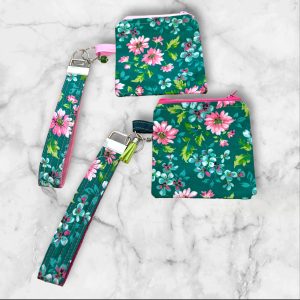 A Floral Fantasy Wristlet Key Fob and Card Wallet with pink and white flowers on a green background.