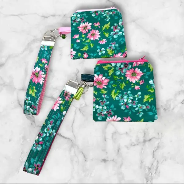 A Floral Fantasy Wristlet Key Fob and Card Wallet with pink and white flowers on a green background.