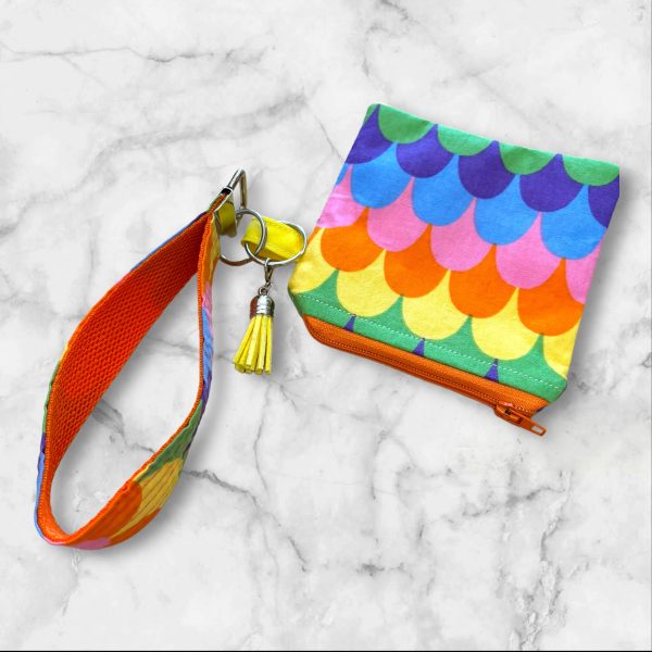 Dive into a sea of vibrant colors with the Rainbow Scales Wristlet Key Fob & Card Wallet. This playful design features a stunning array of bright hues arranged in a fun, scale-like pattern. Perfect for those who love bold accessories, this set will keep your essentials secure while adding a splash of color to your day. Key Features: • Made with 100% cotton and durable nylon webbing • Wristlet measures approximately 1.5" x 7" • Zipper pouch measures approximately 4.5" x 4.5" • Ideal for keys, IDs, cards, and small items • Unique pattern placement for a one-of-a-kind look Bring a burst of color into your life with the Rainbow Scales Wristlet and Card Wallet—perfect for adding a touch of fun to any outfit.