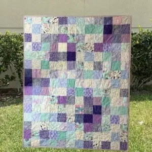 A whimsical Mermaids and Unicorns Quilt featuring playful fabrics with mermaids, unicorns, and floral patterns in shades of purple, teal, and pastel colors, measuring 52” x 65”.