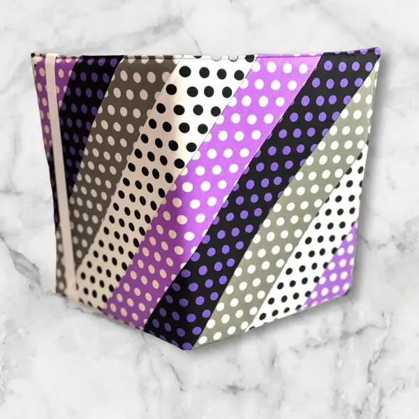 Polka Dot Striped composition notebook cover featuring stripes of black, grey, white, and purple polka dots with a white elastic band.