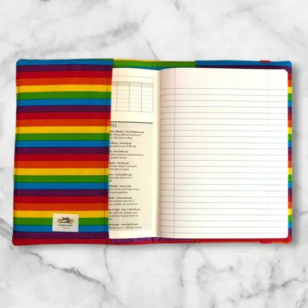 Rainbow Stripe composition notebook cover with vibrant strips of red, orange, yellow, green, blue, and purple fabric and a red elastic band.