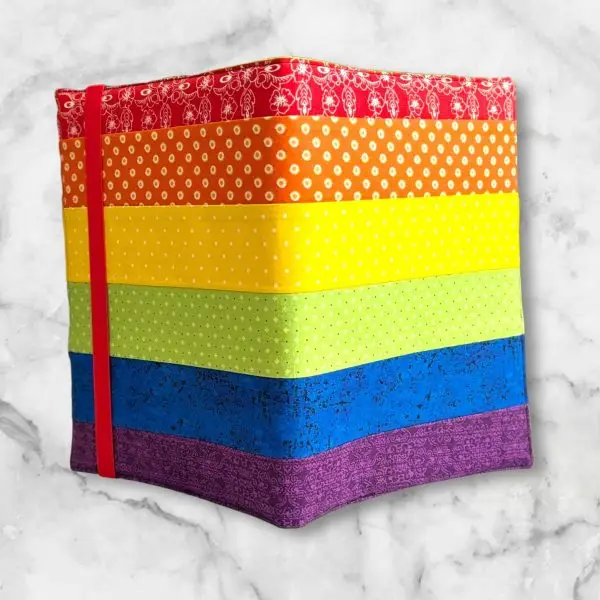 Rainbow Stripe composition notebook cover with vibrant strips of red, orange, yellow, green, blue, and purple fabric and a red elastic band.