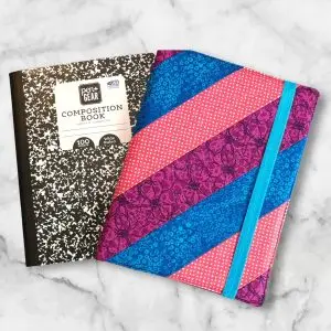 Pink, Purple and Blue Diagonal composition notebook cover with vibrant stripes and a blue elastic band.