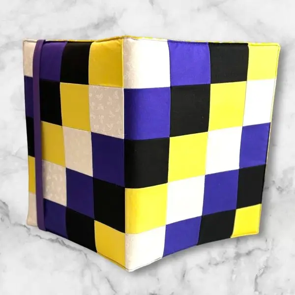 Checkerboard pattern composition notebook cover featuring yellow, white, purple, and black squares with a matching elastic band.