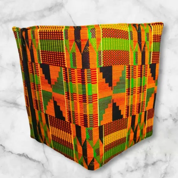 Kente-inspired composition notebook cover featuring bold oranges, greens, blacks, and yellows in intricate geometric patterns with an elastic band.