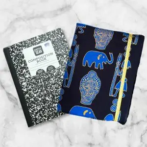 Blue African Symbols composition notebook cover featuring blue symbols with gold accents on a navy blue background with a gold elastic band.