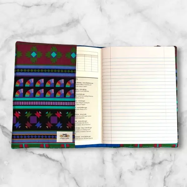 Vibrant geometric composition notebook cover featuring deep reds, greens, purples, and blues with a red elastic band.