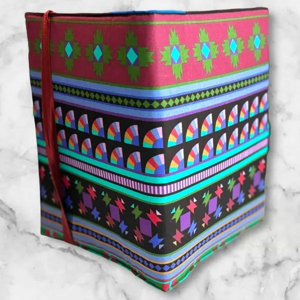 Vibrant geometric composition notebook cover featuring deep reds, greens, purples, and blues with a red elastic band.