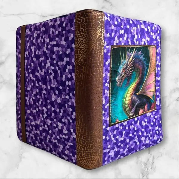 Dragon Fyre composition notebook cover with a detailed dragon on a deep background, accented with purple geometric fabric and brown spine.