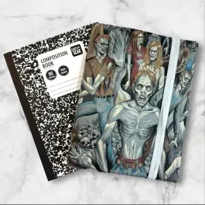 A composition notebook cover showcasing a detailed illustration of a crowd of zombies in various eerie poses. The cover has a gray elastic band securing it closed and is displayed next to a standard composition notebook.