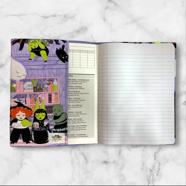 A composition notebook cover with a fabric design showcasing witches, ghosts, and Halloween-themed scenes in bright colors, predominantly purple, green, and orange. The cover is displayed with a standard composition notebook.