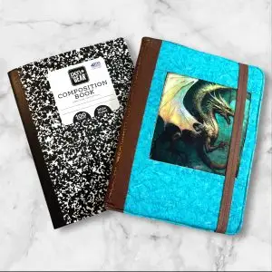 Quilted composition notebook cover with a turquoise and brown design, featuring a detailed illustration of a dragon on the front and an elastic closure.