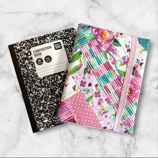 Quilted composition notebook cover with a vibrant floral design in shades of pink, green, and teal, featuring diagonal stripes and an elastic closure.