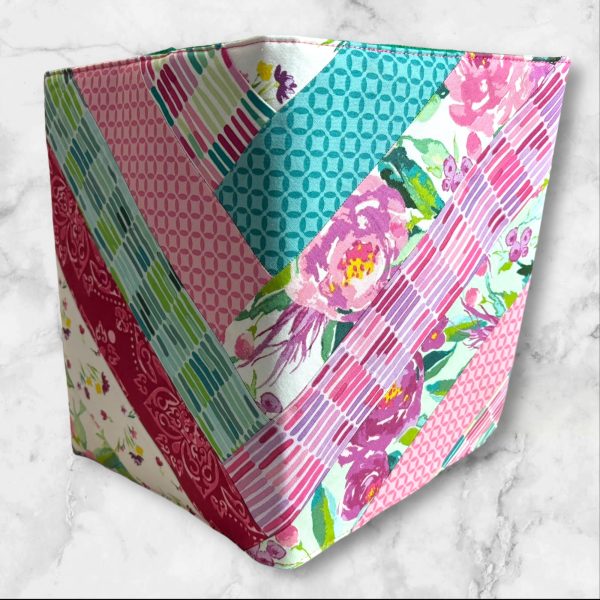 Quilted composition notebook cover with a mix of pink, green, and floral striped patterns, creating a fresh and elegant look.