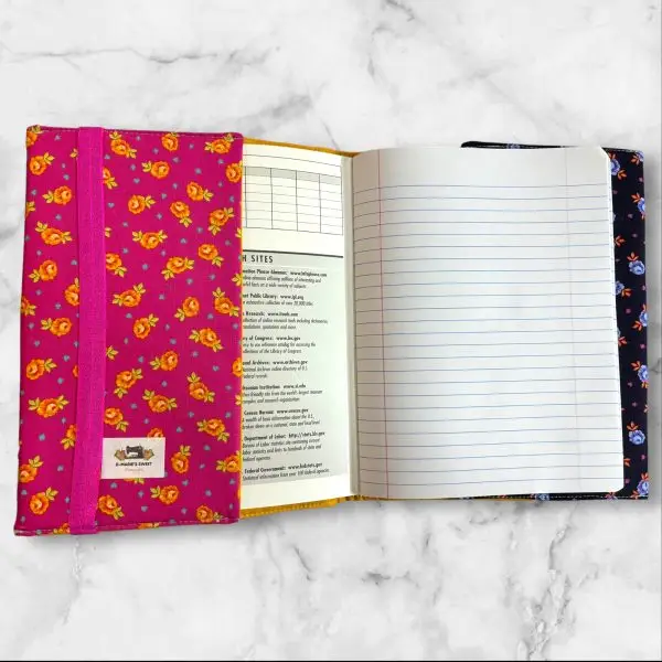 Quilted composition notebook cover with a pink and yellow design, showcasing a playful Cheshire Cat print surrounded by bright floral patterns.