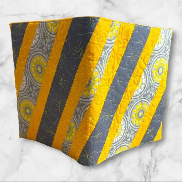 Quilted composition notebook cover with a stylish yellow and gray striped design, adorned with a floral pattern for an elegant look.