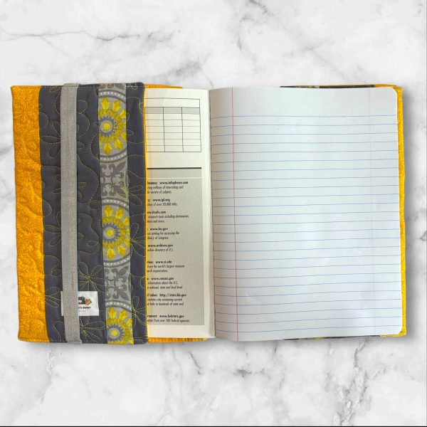 Quilted composition notebook cover with a stylish yellow and gray striped design, adorned with a floral pattern for an elegant look.