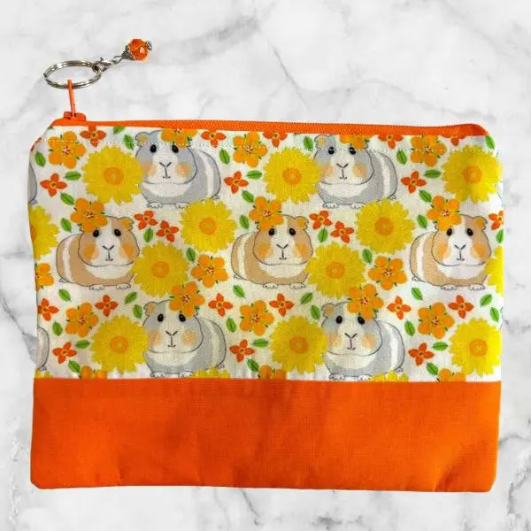 Guinea Pig Floral Zipper Pouch with orange base, featuring guinea pigs and vibrant flowers on a light cream background.