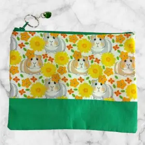 Guinea Pig Floral Zipper Pouch with green base, featuring guinea pigs and flowers on a cream background.