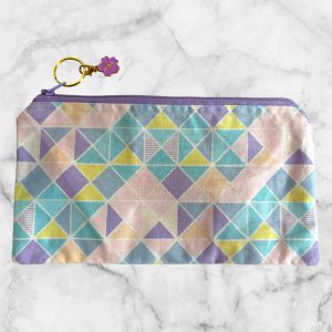 Pastel geometric zipper pouch with a lavender zipper and triangle pattern in soft shades of pink, blue, yellow, and lavender.