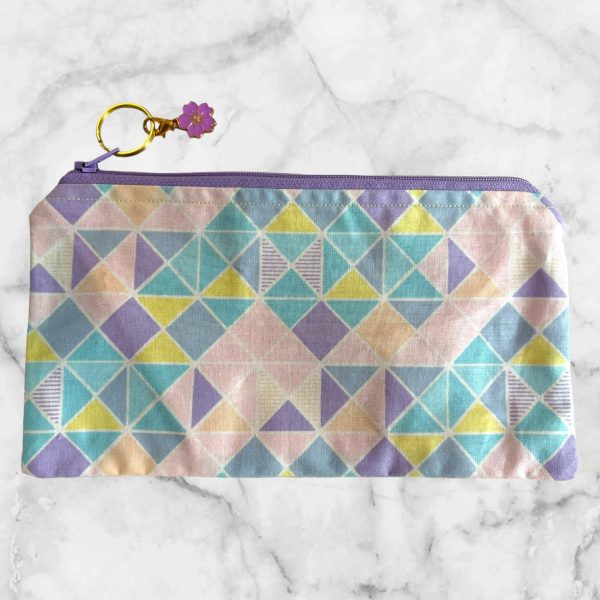 Pastel geometric zipper pouch with a lavender zipper and triangle pattern in soft shades of pink, blue, yellow, and lavender.