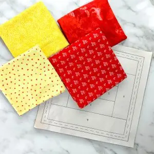 Cheerful Harvest Tones Log Cabin Paper Piecing Quilt Kit with red and yellow fabric and quilt block pattern.