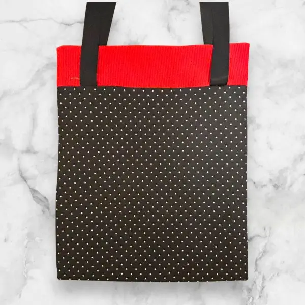 quilted tote bag featuring a geometric quilt block front with red accents and a polka dot-patterned back.